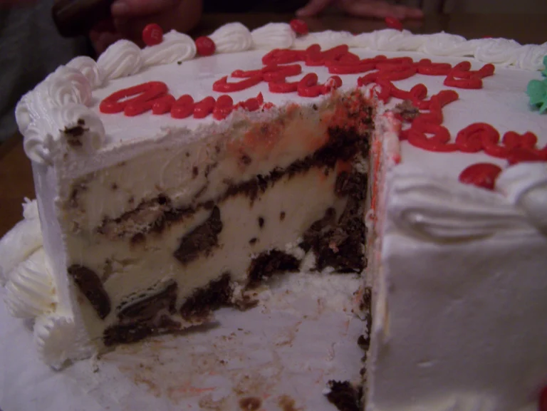 A close-up of a Dairy Queen ice cream cake, featuring layers of rich chocolate and vanilla ice cream, crunchy chocolate pieces, and creamy frosting decorated with colorful piping.