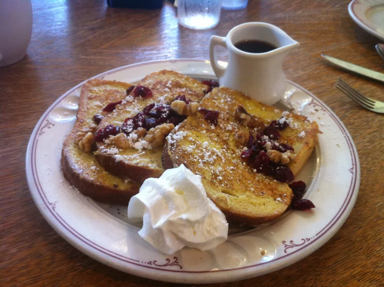 A delicious plate of French toast topped with fresh cranberries and a dusting of powdered sugar.