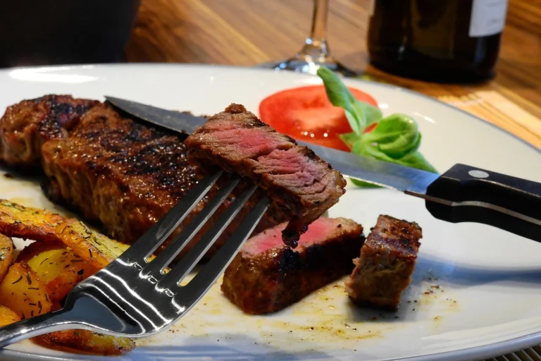 A juicy, perfectly seared Delmonico steak served on a wooden board with a side of grilled vegetables and garnished with fresh herbs.