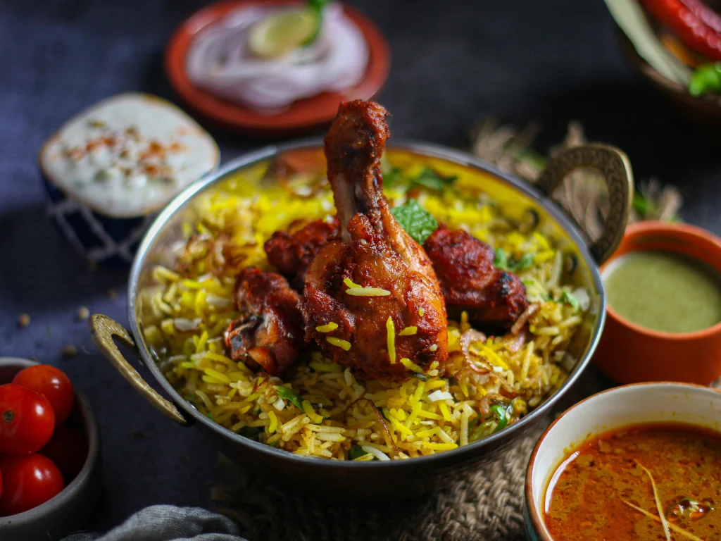 A plate of flavorful chicken biryani garnished with fresh coriander, fried onions, and a side of raita.