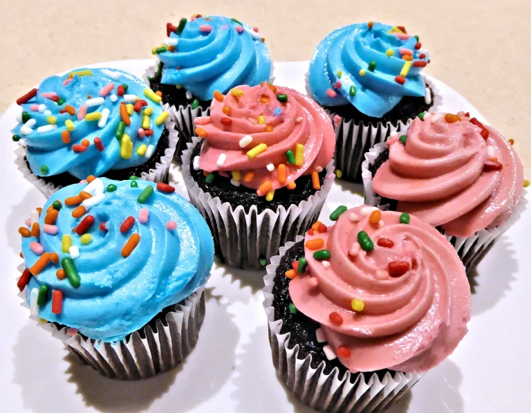 An assortment of colorful mini cupcakes topped with frosting and sprinkles, arranged on a tray.