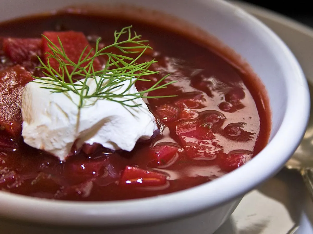 Borscht – A vibrant red beet soup served with a dollop of sour cream and fresh dill, a classic dish in Russian cuisine.