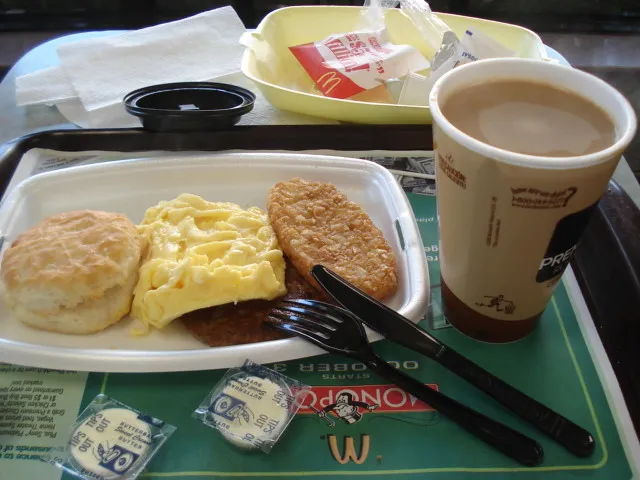 A table set with a homemade McDonald's-style breakfast including Egg McMuffins, hash browns, hotcakes, and coffee