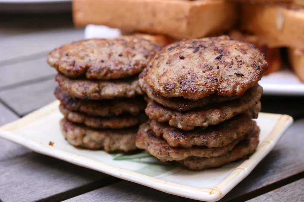 Round, uncooked sausage patties placed on parchment paper, ready for cooking.