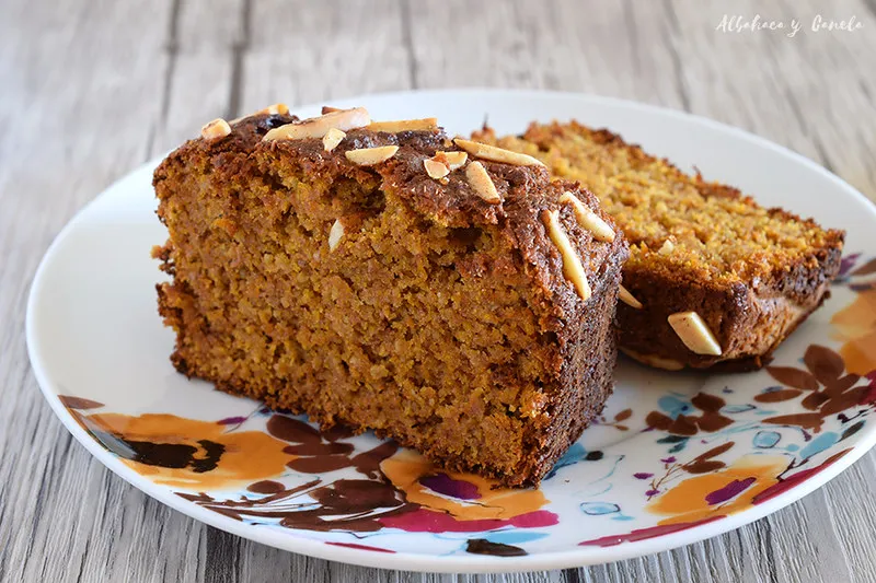 A slice of vegan oat cake on a wooden cutting board with a drizzle of nut butter.