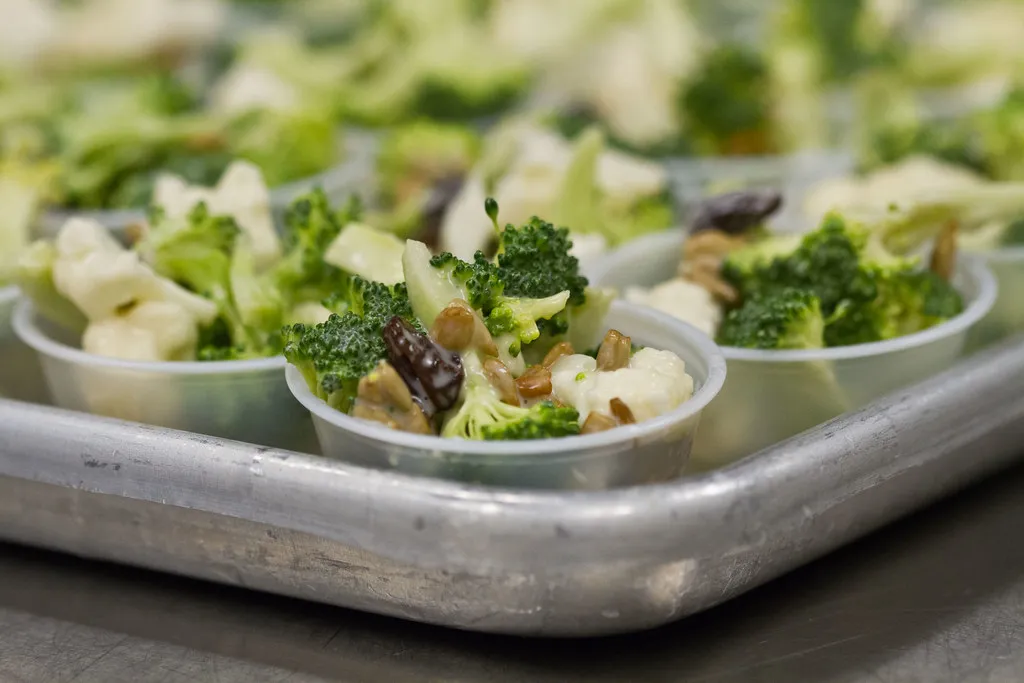 Fresh broccoli and cauliflower florets on a wooden cutting board, ready for salad preparation.