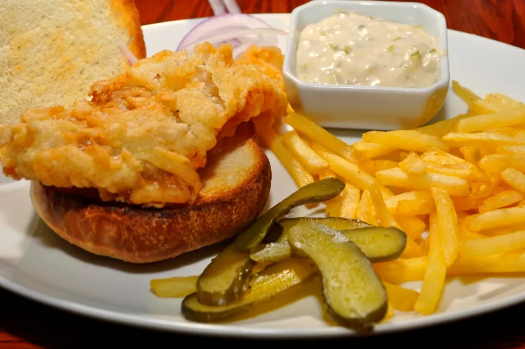 Close-up of a breakfast sandwich with a creamy, smooth sauce drizzled over layers of egg, cheese, and ham on a toasted bun