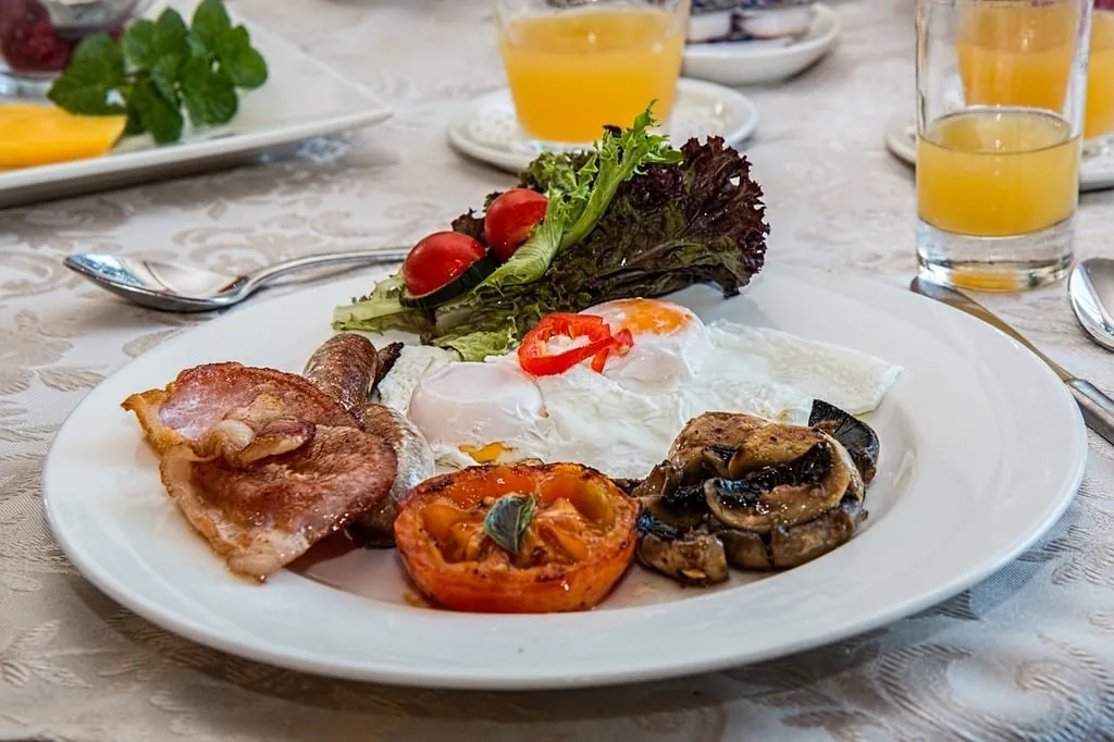 A high-protein breakfast plate featuring scrambled eggs with turkey sausage, sautéed spinach, a side of Greek yogurt topped with almonds and honey, and a fresh slice of whole-grain toast