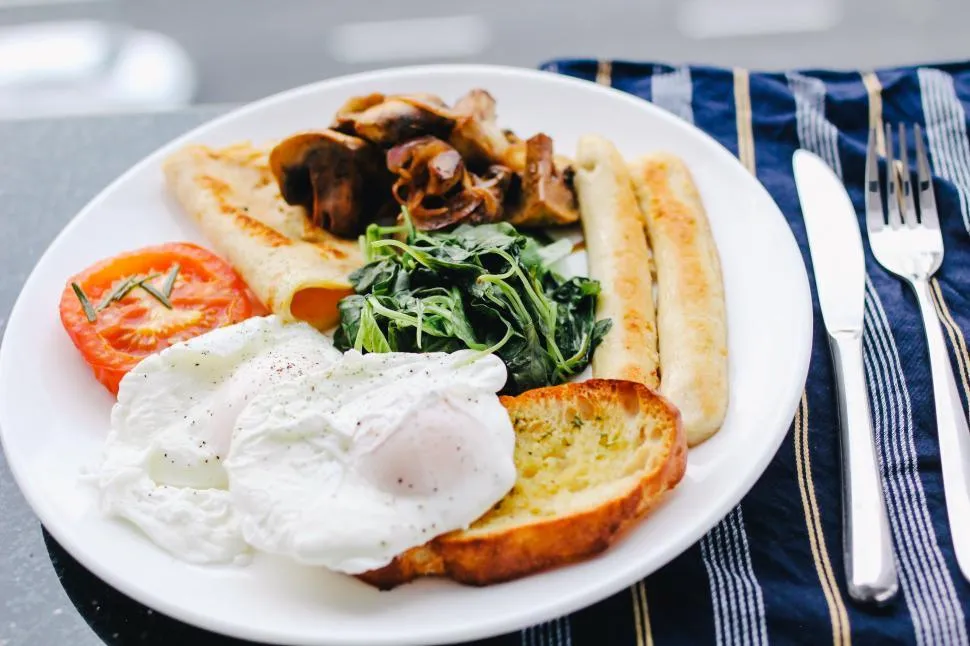 A Mediterranean breakfast plate with Greek yogurt drizzled with honey, topped with walnuts and pomegranate seeds, a side of fresh cucumber and tomato slices, and whole-grain toast with olive oil.