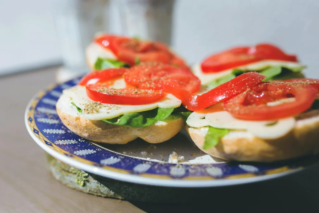 Flat lay of ingredients: sourdough slices, avocado, tomato, olive oil, lemon, and salt on a kitchen counter.