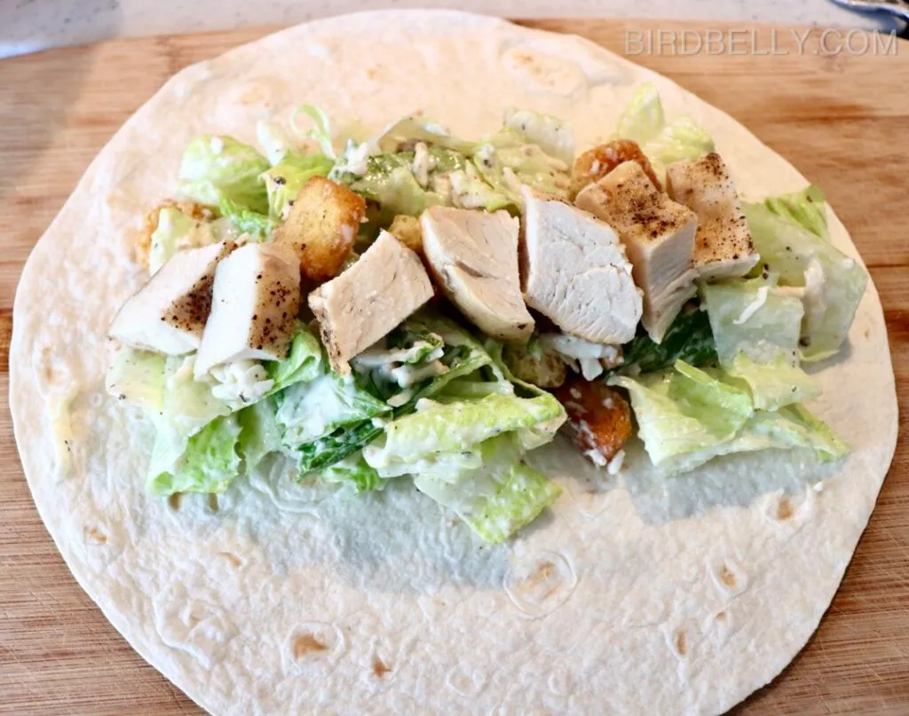 Step-by-step guide to making a Chicken Caesar Wrap with grilled chicken, fresh romaine lettuce, Caesar dressing, and Parmesan cheese in a soft tortilla