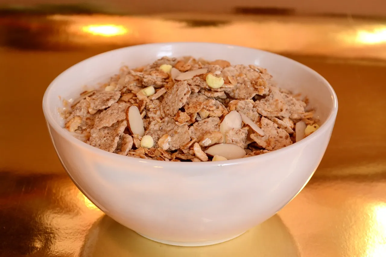 A close-up of a bowl filled with plain whole-grain cereal on a wooden breakfast table