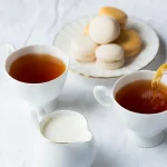 Steaming cup of British Breakfast Tea with a teapot, perfect for brewing the ultimate morning tea