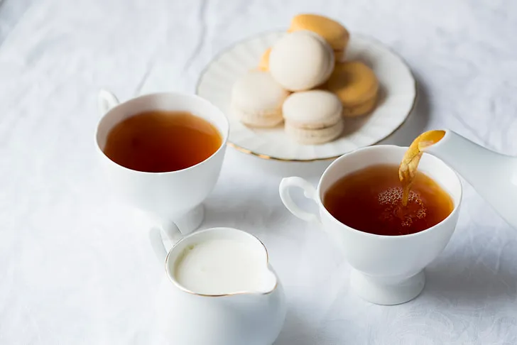 Steaming cup of British Breakfast Tea with a teapot, perfect for brewing the ultimate morning tea