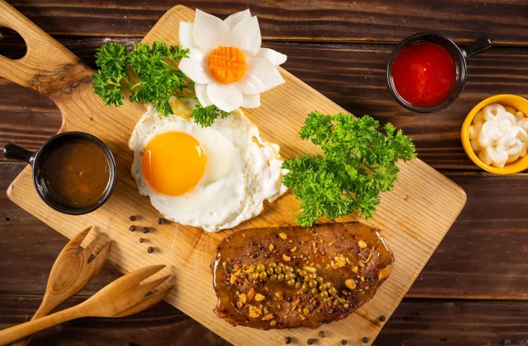 Delicious steak and eggs breakfast on a plate, with a perfectly seared steak, sunny-side-up eggs, and crispy potatoes.