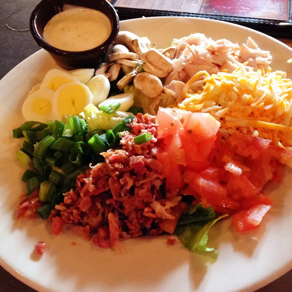 "Colorful Cobb salad bowl with fresh vegetables and creamy dressing"