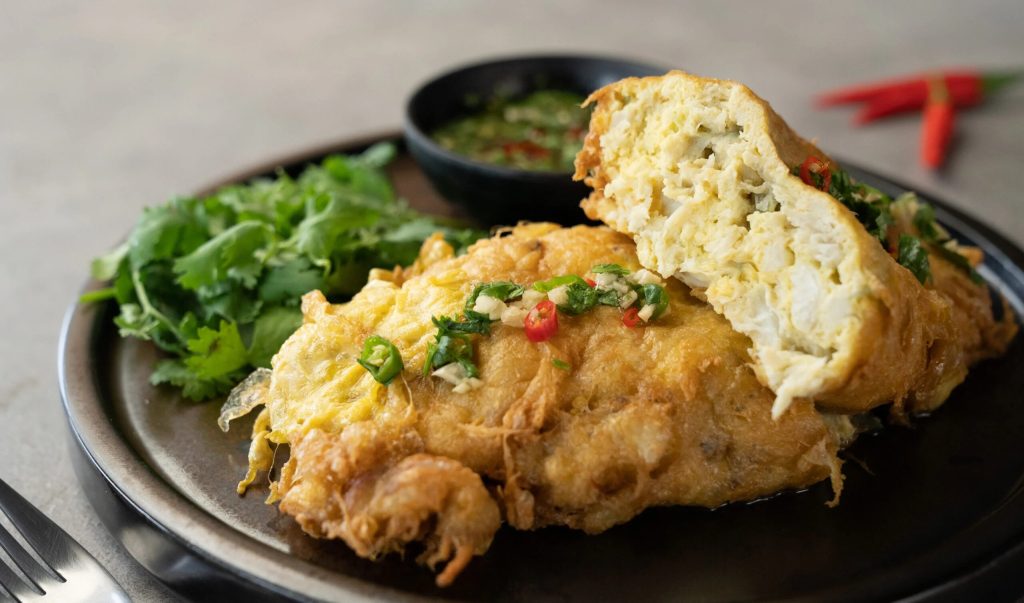 Crab omelette cooking in a non-stick pan, ready to be folded