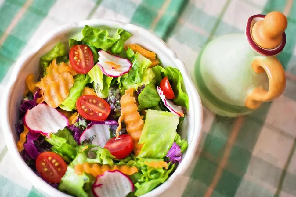 A vibrant green salad with lettuce, cherry tomatoes, cucumbers, and bell peppers in a bowl