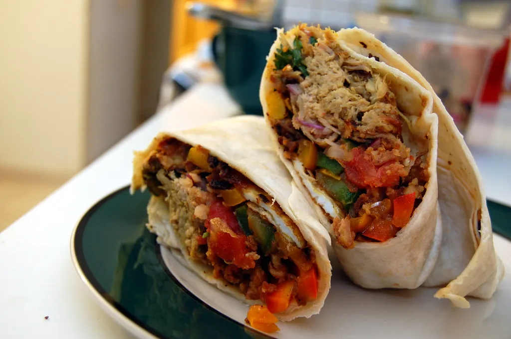 Healthy breakfast burrito with avocado, spinach, and grilled chicken wrapped in a soft tortilla