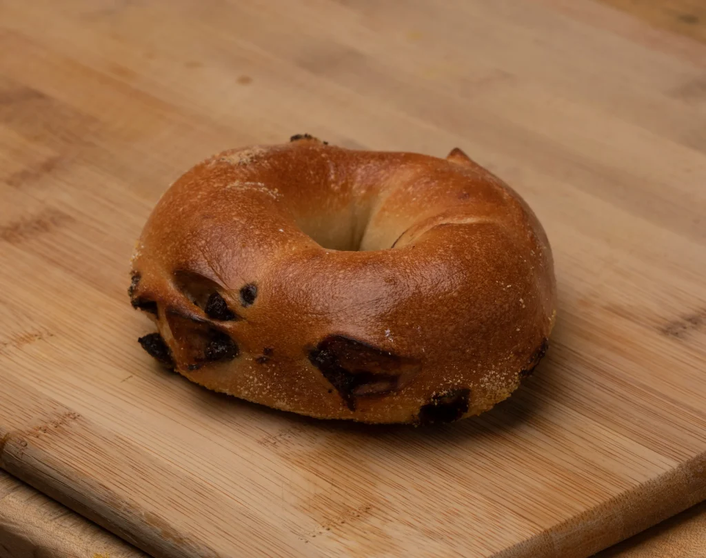 Freshly baked chocolate chip bagel sliced in half, showing melted chocolate chips and soft, fluffy texture inside.