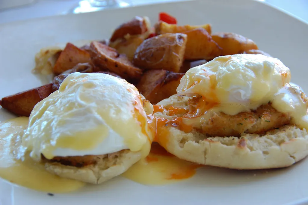 Fresh ingredients for crab cake eggs benedict including crab meat, eggs, English muffins, and lemon