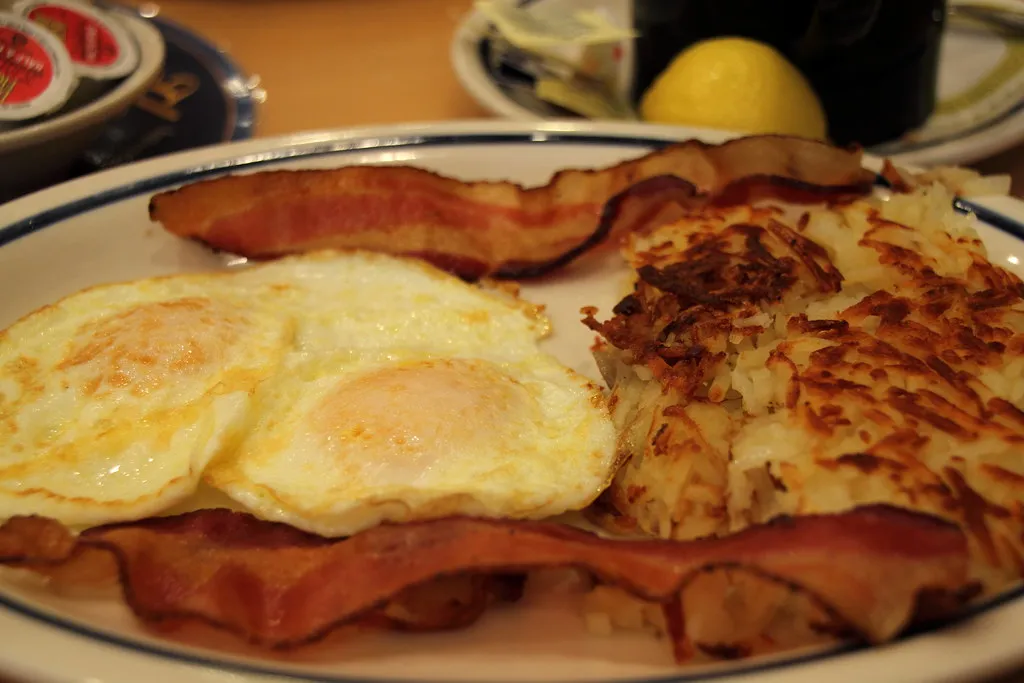 Delicious morning meal with hash browns, bacon strips, and breakfast sausage