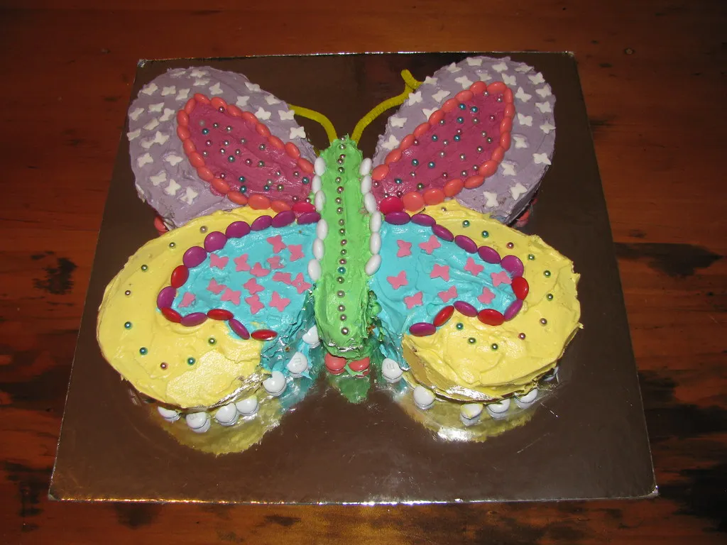 Elegant butterfly cake with soft buttercream wings, adorned with edible pearls and sugar butterflies, ideal for a whimsical birthday or baby shower.