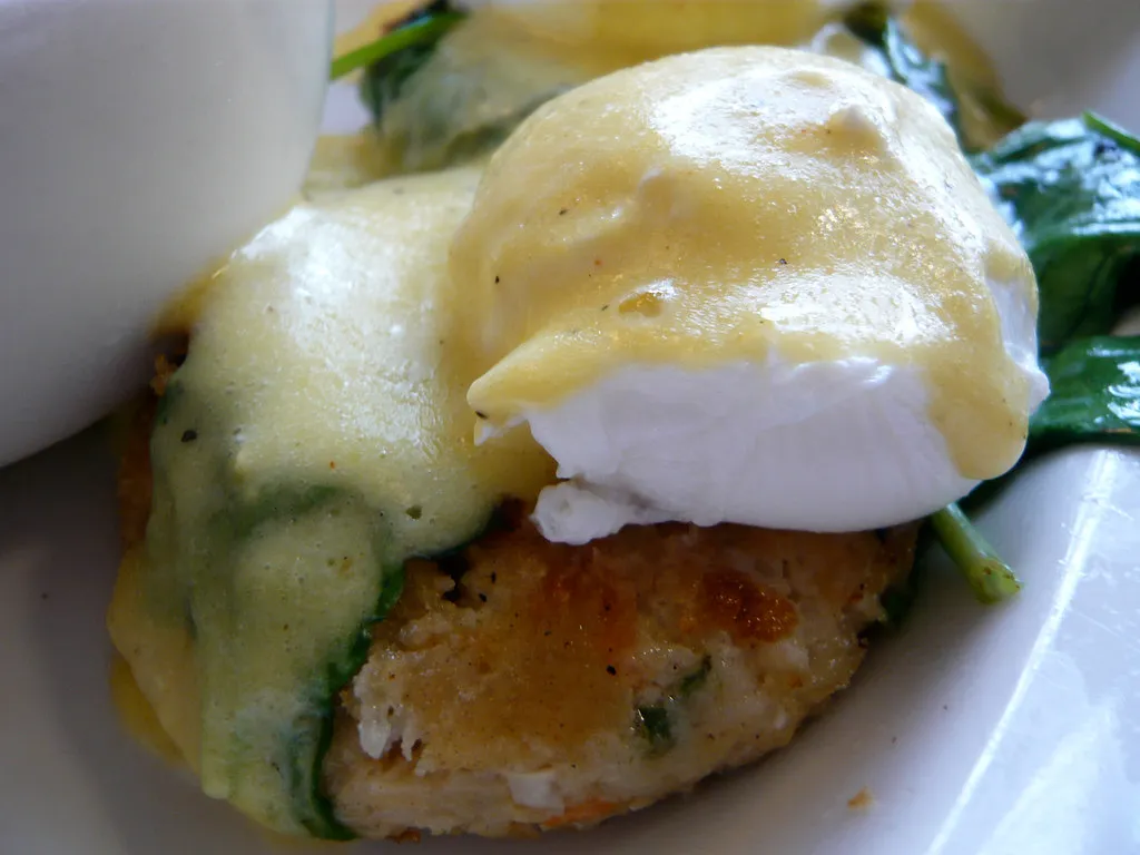 Perfectly poached egg topped with hollandaise sauce on a crispy crab cake