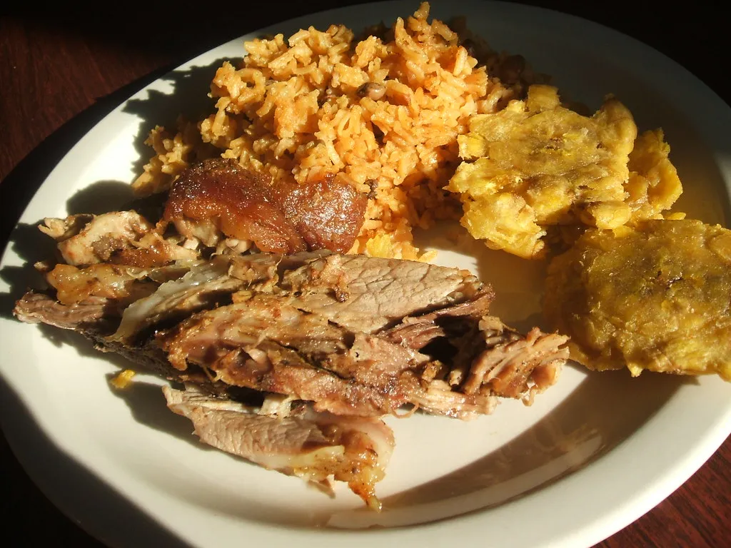 A plate featuring succulent slices of lechón (roast pork) served alongside a generous helping of Arroz con Gandules, ideal for a celebratory meal.