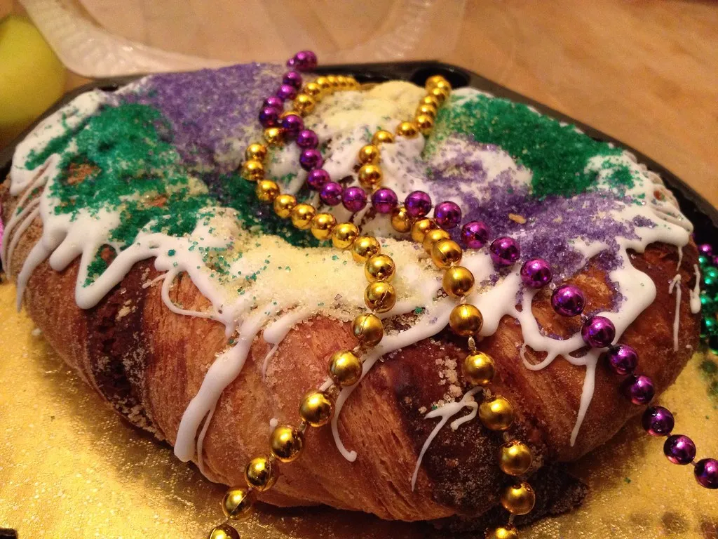 Freshly baked Randazzo’s-style King Cake with purple, green, and gold sugar decoration on a festive Mardi Gras table.