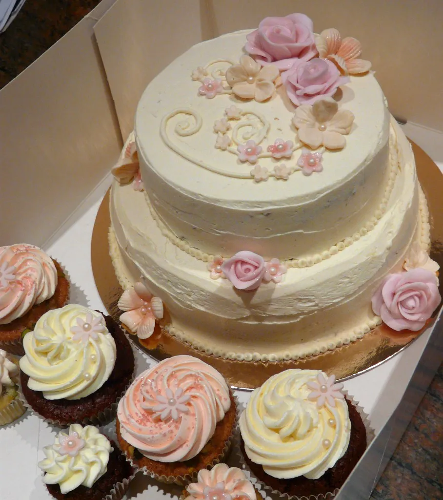 Close-up of hands decorating cupcakes with colorful frosting and sprinkles