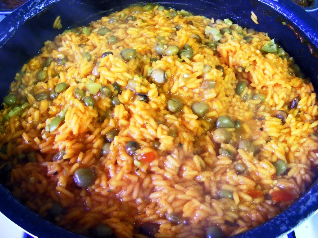 Arroz con Gandules cooking in a pot on the stove, with the rice absorbing the rich, flavorful broth and sofrito.