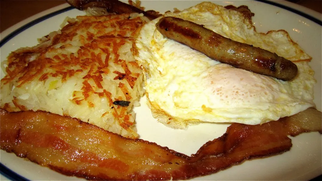 Golden brown hash browns with sausage, bacon, and eggs