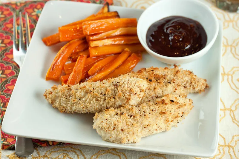 Close-up of chicken tenders being dipped in breadcrumbs for a crispy coating