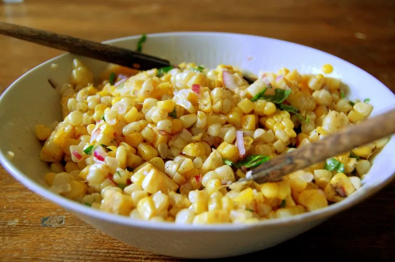 Colorful Frito Corn Salad with corn kernels, diced bell peppers, shredded cheese, and crunchy Fritos chips in a glass bowL