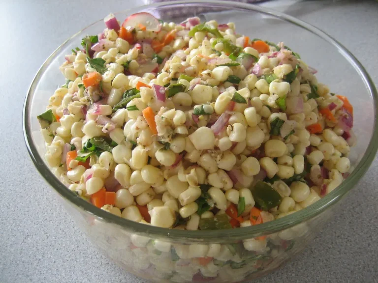 Colorful bowl of Frito Corn Salad with corn, red bell peppers, shredded cheddar cheese, and crunchy Fritos chips