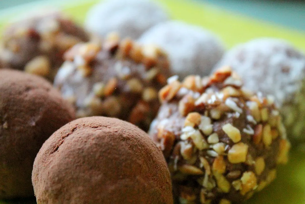 Delicious raw chocolate truffles made with cacao, nuts, and coconut, rolled in shredded coconut and arranged on a plate