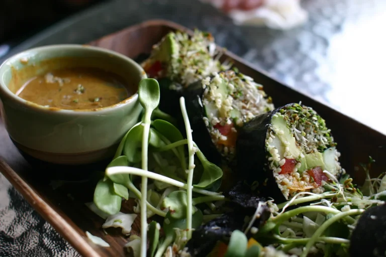 A vibrant spread of raw vegetarian meals including colorful salads, veggie wraps, and fresh smoothies, all served on wooden plates and bowls.