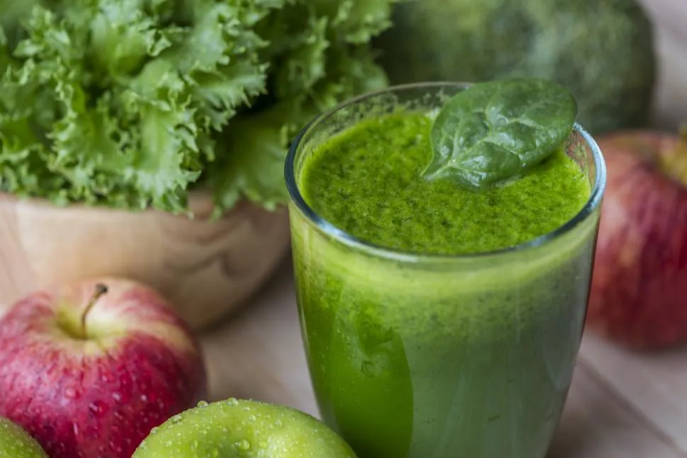 Refreshing green smoothie made with spinach, banana, and avocado, served in a glass with a garnish of mint leaves.