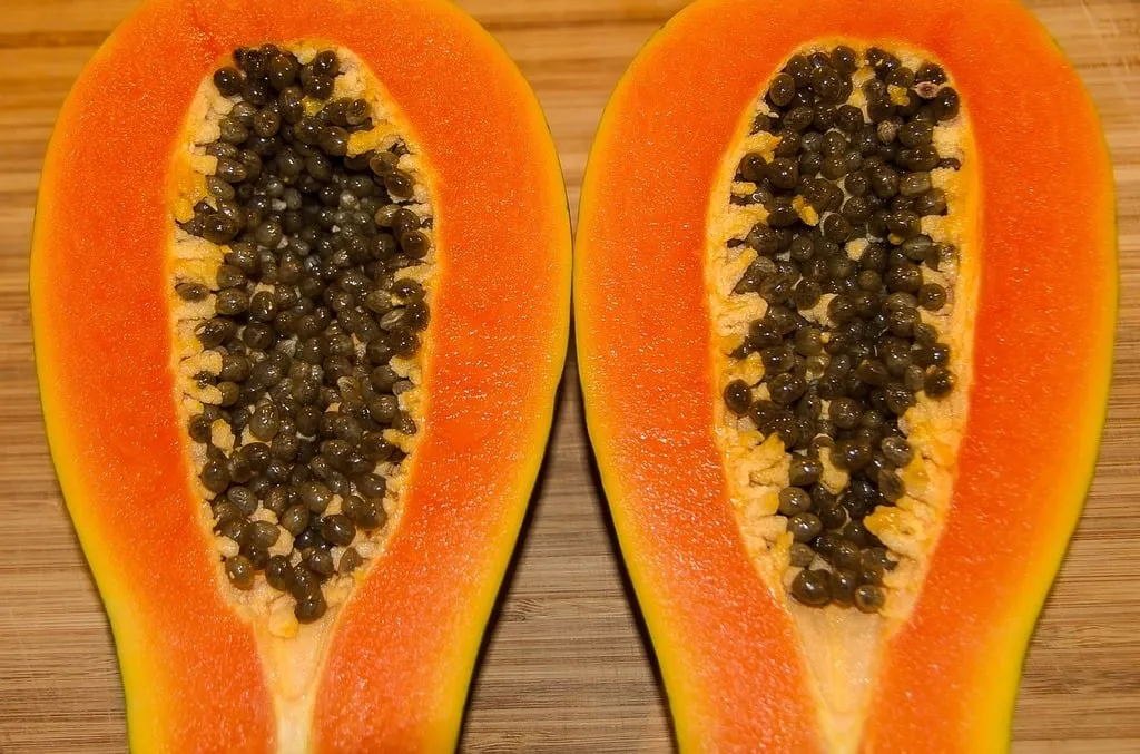 Whole ripe papaya with yellow-orange skin on a white background