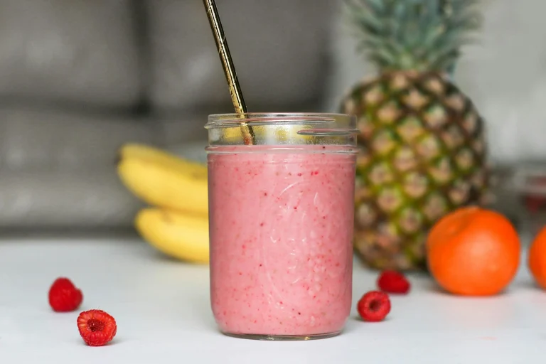 olorful assortment of healthy smoothies in glass jars with fresh fruits and greens on a wooden table