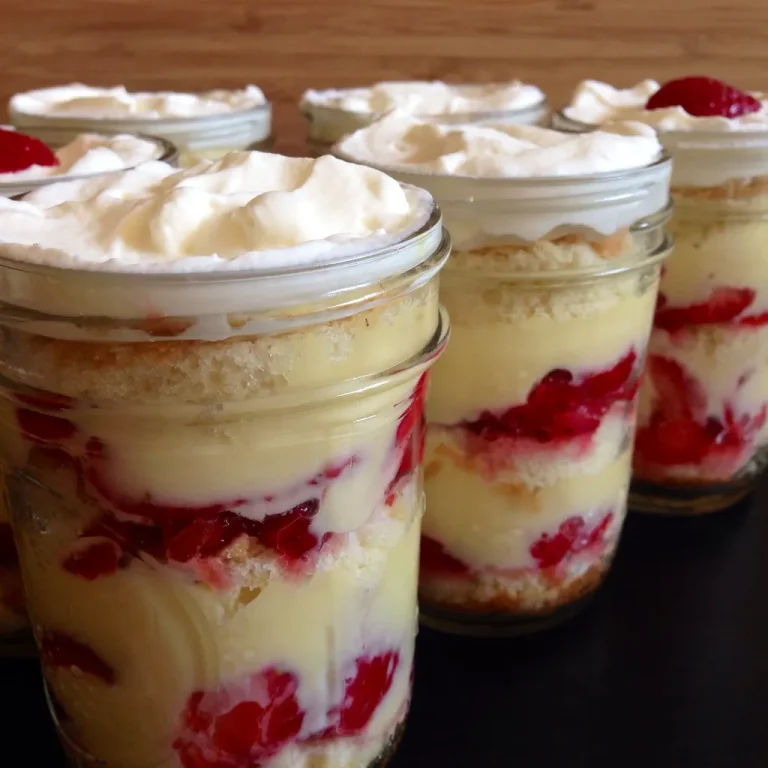 Strawberry shortcake in a jar with layers of vanilla cake, whipped cream, and sliced strawberries