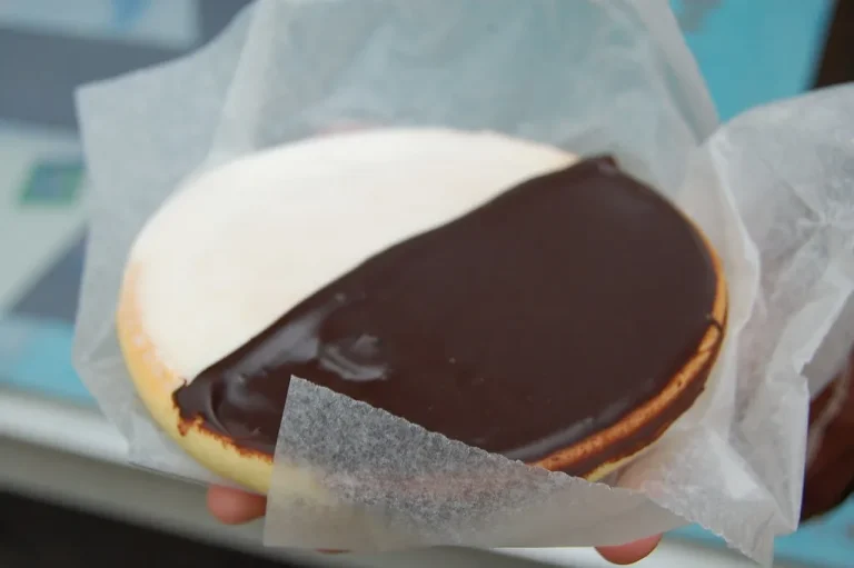 Layered black and white cookie dessert topped with whipped cream and chocolate drizzle in a glass dish