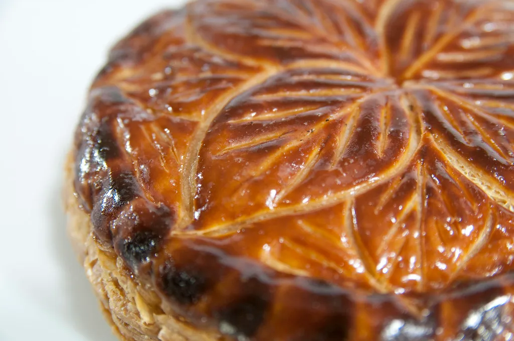 Golden baked Galette des Rois with decorative top scoring and paper crown for Epiphany celebration