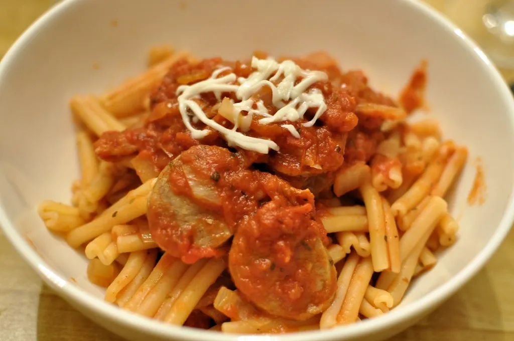 Plate of smoked sausage pasta garnished with Parmesan cheese and parsley