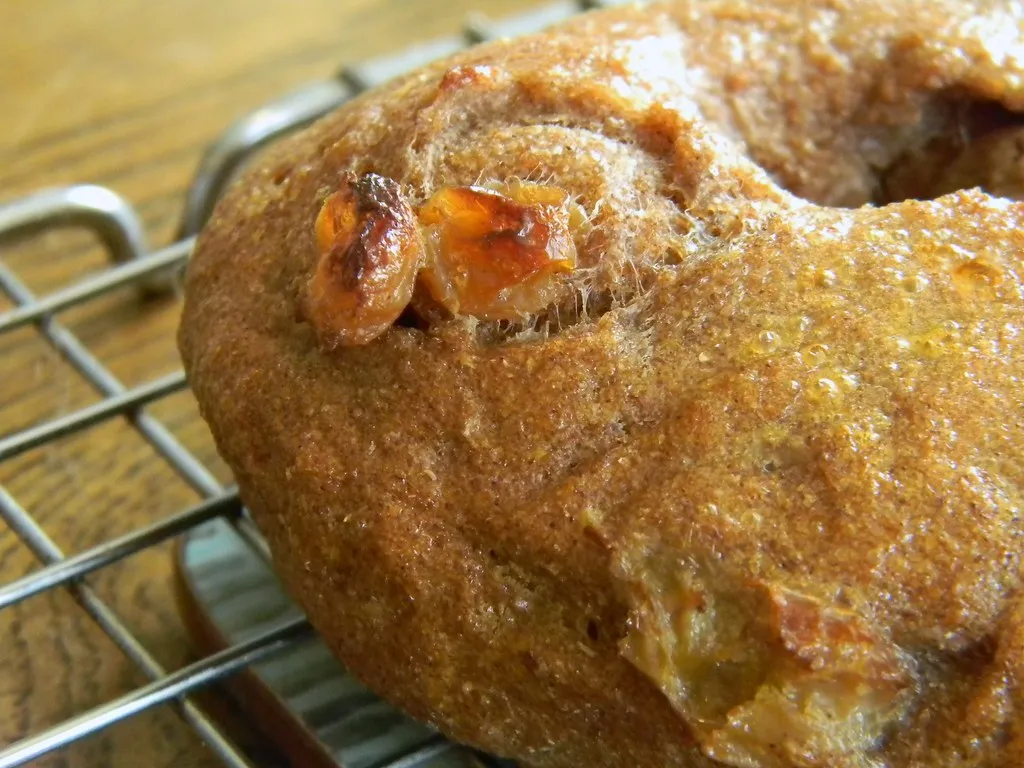 Golden brown cinnamon raisin bagels fresh out of the oven on a parchment-lined baking sheet