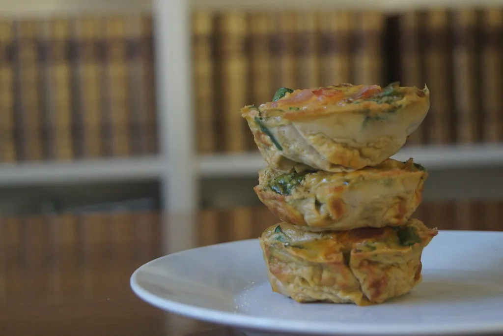 Freshly baked bacon and sausage egg muffins in a muffin tin on a wooden table