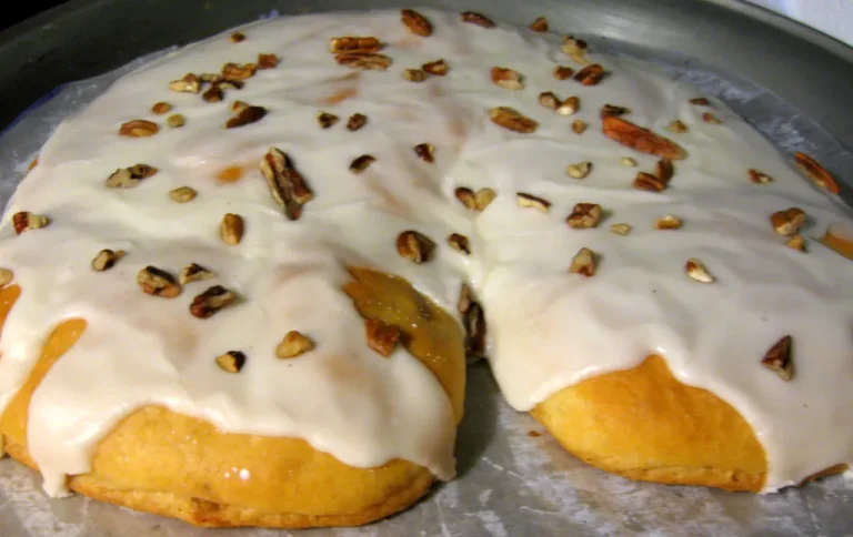 Homemade Danish Kringle topped with vanilla glaze and almonds, served on a cozy breakfast table with coffee and fruit.