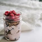 Layered Greek yogurt berry parfait in a clear glass jar, topped with granola and fresh berries for a healthy single-serve dessert.