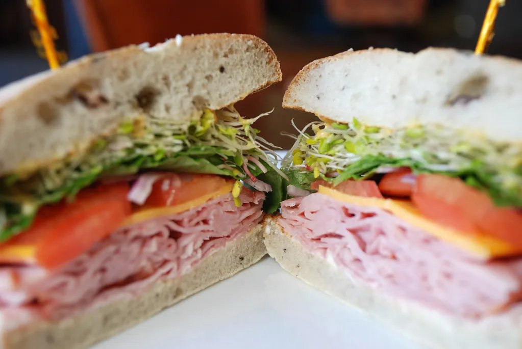 Italian deli sandwich with layers of meats, cheese, lettuce, and tomato on a rustic roll